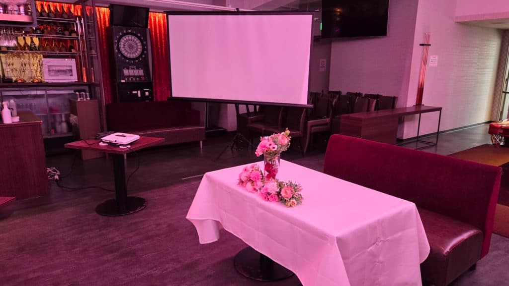 スライド上映用のスクリーンと装花をセッティングした会場